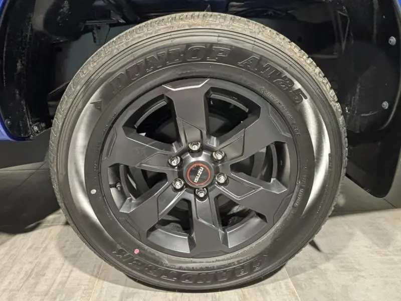 Gros plan sur la roue avant droite noire avec jante alu noire du pick-up Isuzu D-MAX Biarritz Blue Metallic.
