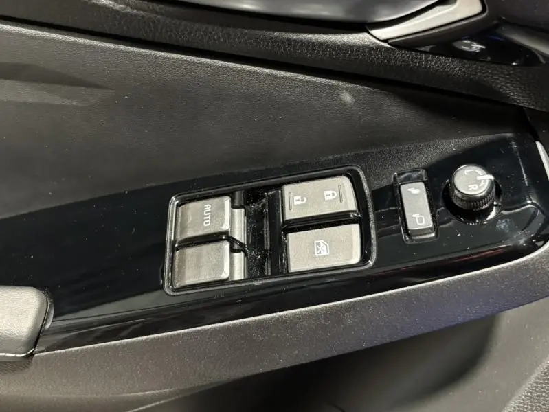 Gros plan sur les commandes de lève-vitres et rétroviseurs côté conducteur de l'Isuzu D-MAX 2025 finition Nitro Sport en noir.