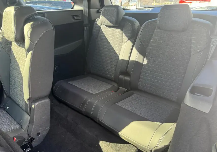 Vue intérieure arrière montrant la troisième rangée de sièges gris du Peugeot 5008 Hybrid 145 e-DCS6 Allure 2025.