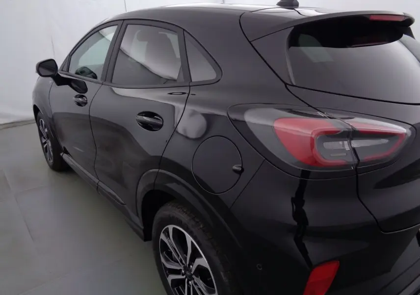 Vue 3/4 arrière côté gauche d'un Ford Puma noir Agate Métal avec jantes alliage bicolores et feux arrière LED distinctifs.