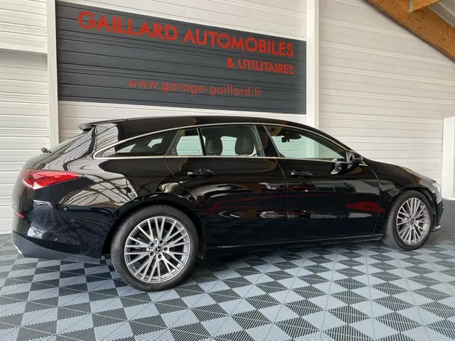 Vue de profil côté gauche d'une Mercedes Classe CLA Shooting Brake noire, avec jantes alliage et intérieur clair visible.