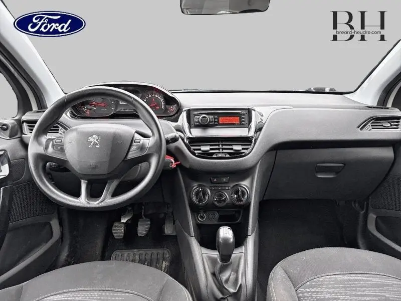 Intérieur de Peugeot 208 blanc Banquise, vue frontale du tableau de bord avec volant et levier de vitesse manuelle.