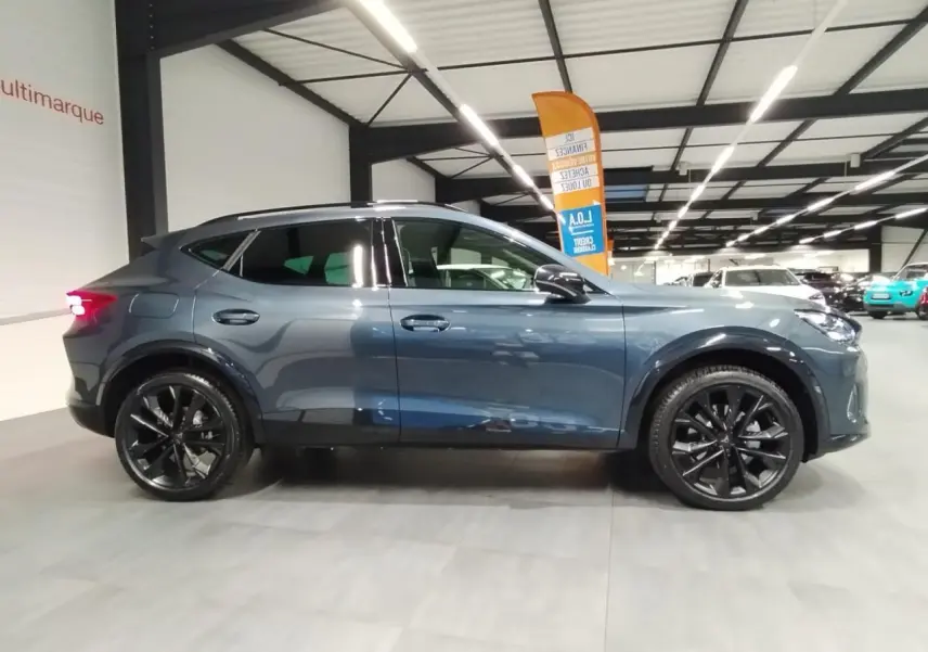 Vue latérale droite d'un CUPRA Formentor 2026 gris Magnetic Tech avec jantes alliage noires en intérieur showroom.