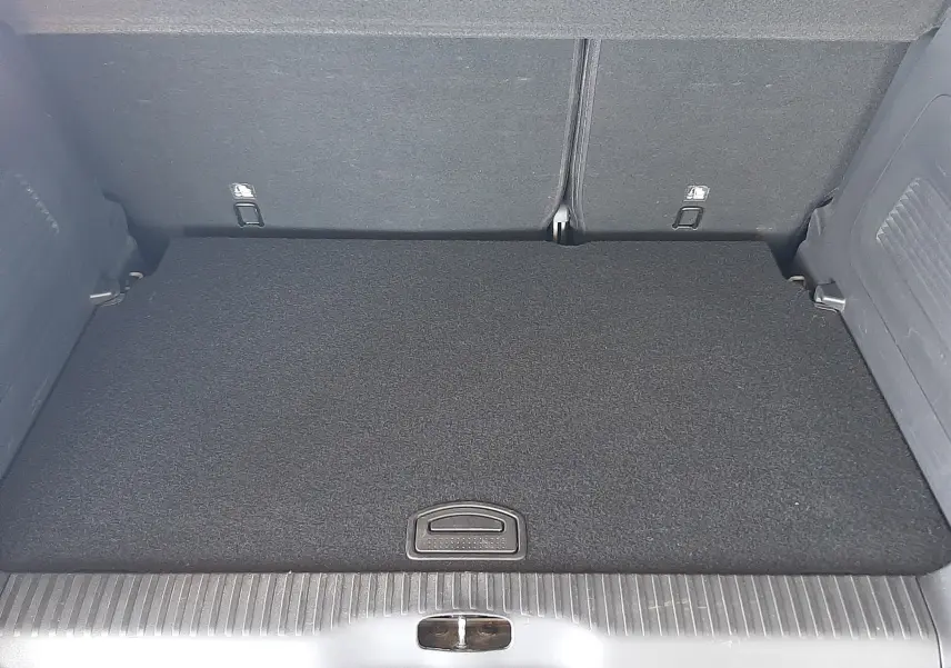 Coffre spacieux et propre du Citroën C3 Aircross 2021, vue intérieure arrière avec tapis noir et poignée centrale.