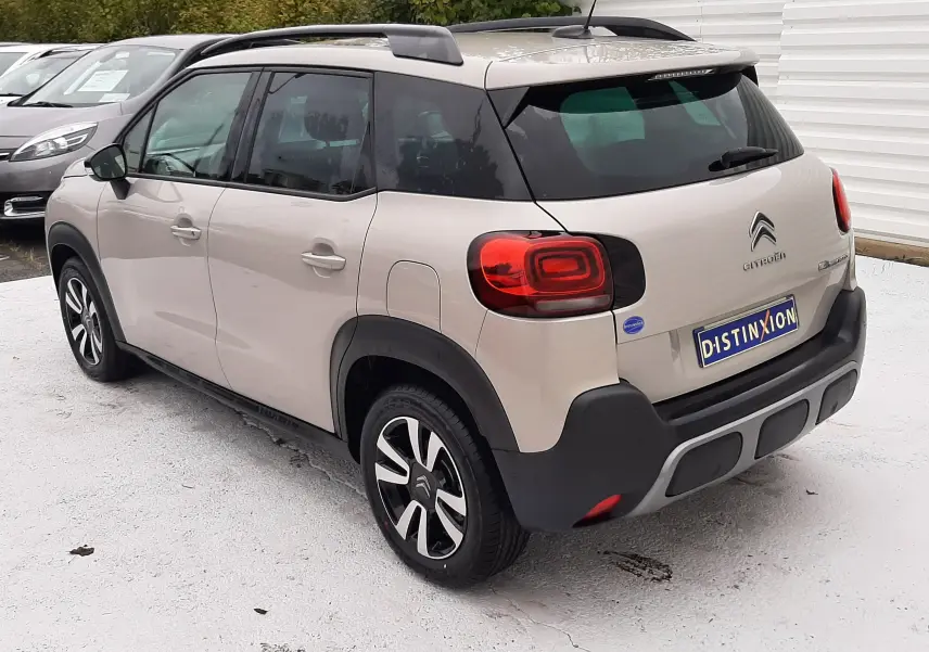 Vue 3/4 arrière droite d'une Citroën C3 Aircross 2021 sable métal avec toit noir et feux arrière distinctifs.
