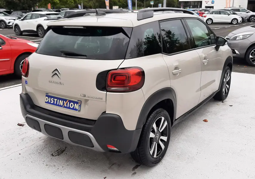 Vue 3/4 arrière droite d'une Citroën C3 Aircross sable métal avec toit noir et jantes alliage distinctives.