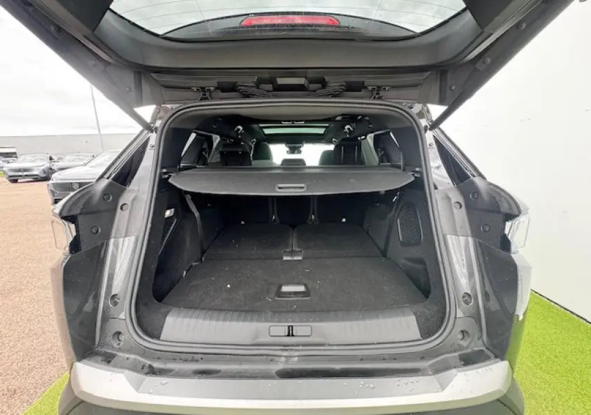 Coffre ouvert vue arrière d’un Peugeot 5008 gris titane avec toit noir, montrant l’espace de chargement et la plage arrière.