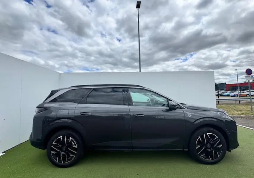 Profil côté droit du Peugeot 5008 gris titane avec toit noir et jantes alliage 19 pouces sur fond urbain.