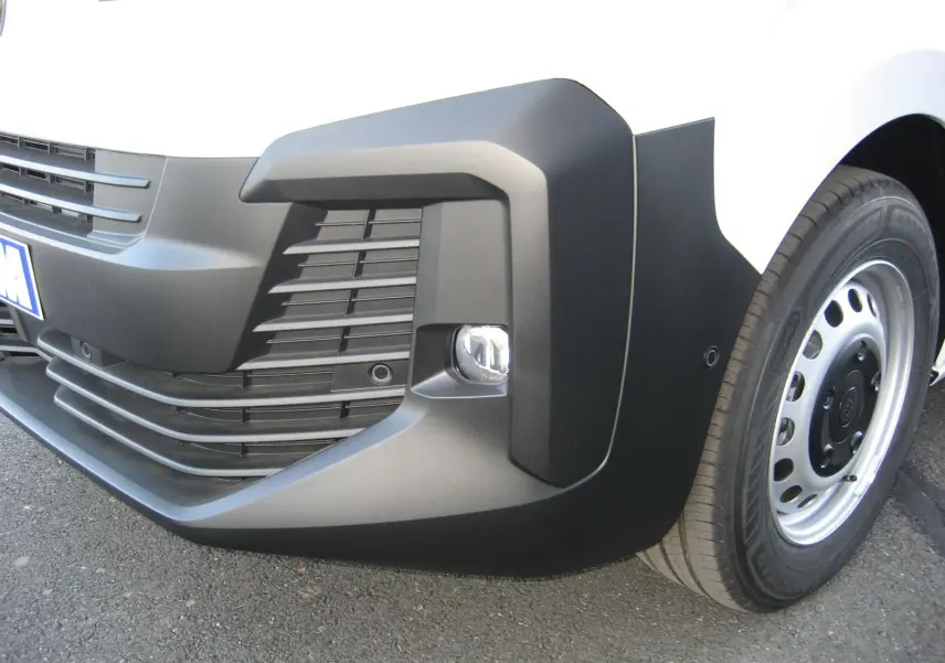 Gros plan sur le pare-chocs avant droit noir et la roue acier du Peugeot Expert Fourgon blanc.