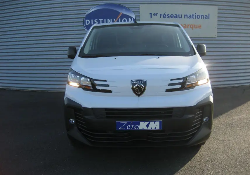 Vue de face d'un Peugeot Expert Fourgon blanc avec feux allumés et logo lion distinctif sur calandre noire.