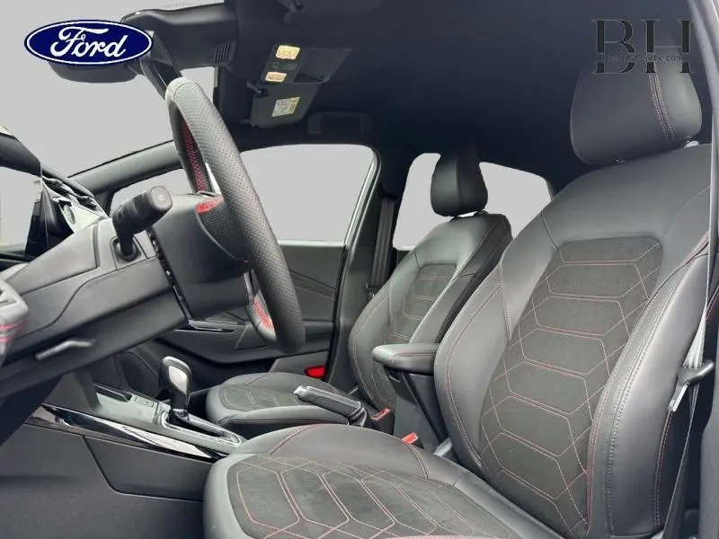 Intérieur avant du Ford Puma 2025, sièges sport noirs avec surpiqûres rouges et volant multifonction visible côté gauche.