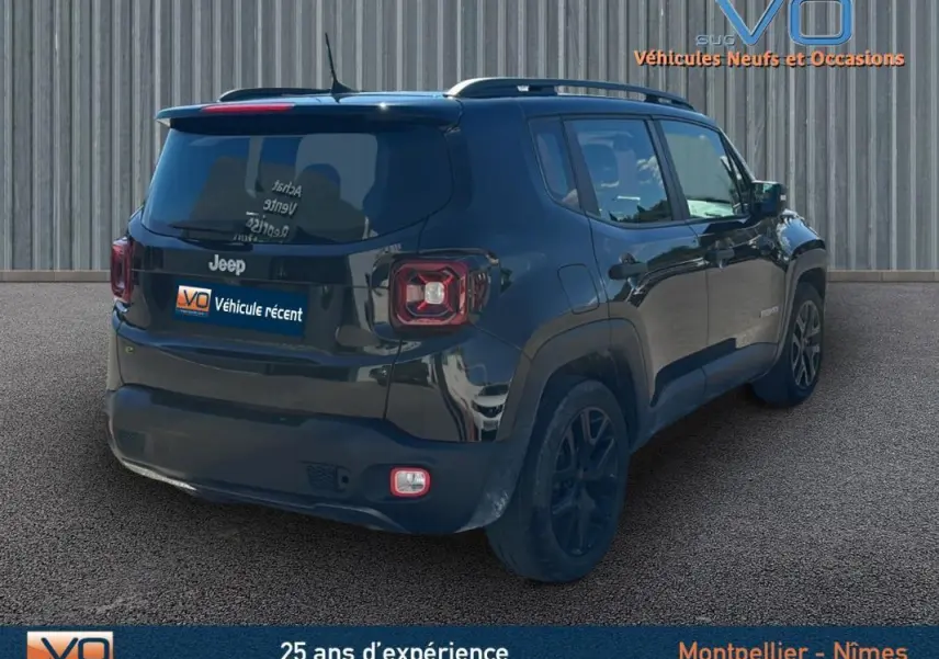 Jeep Renegade noir vue 3/4 arrière droit, avec barres de toit et jantes alliage 18 pouces sur sol goudronné.
