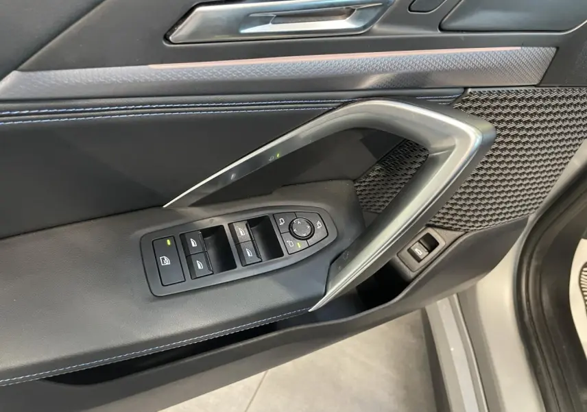 Gros plan sur la porte côté conducteur du BMW X1 xDrive 20d 2024 en Spacesilber Metallic, avec commandes des vitres et insert décoratif.