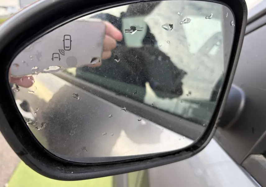 Rétroviseur côté droit gris schiste métal du Dacia Jogger 2025 avec icône de détection d'angle mort visible.