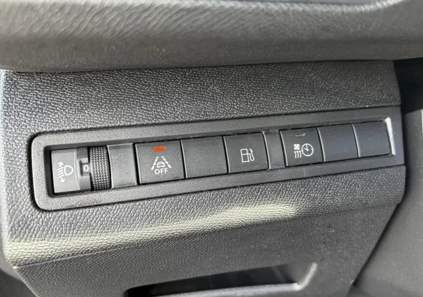 Gros plan sur les commandes noires du tableau de bord du Peugeot 3008 Plug-in Hybrid 2024, avec boutons d'assistance et réglages lumineux.