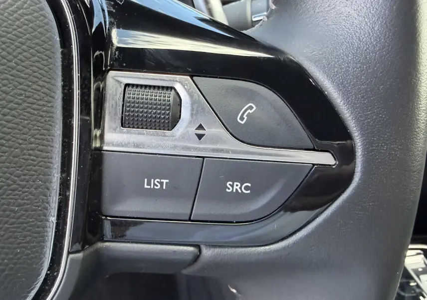 Gros plan sur les commandes du volant côté gauche du Peugeot 3008 noir Perla, boutons appel et réglages audio.