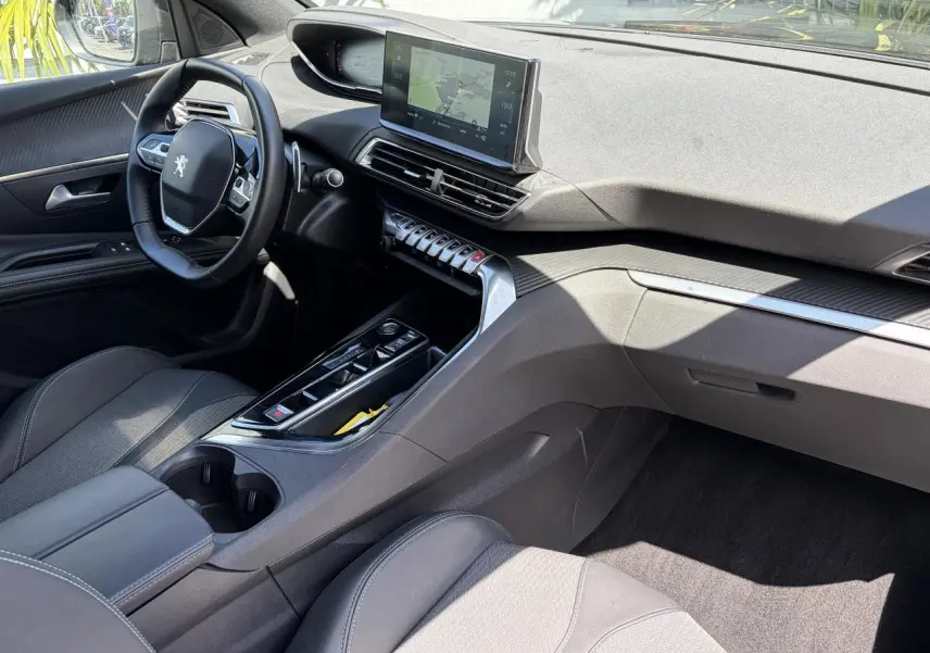Vue intérieure côté conducteur du Peugeot 3008 Plug-in Hybrid 2024, tableau de bord noir avec écran tactile et volant compact.