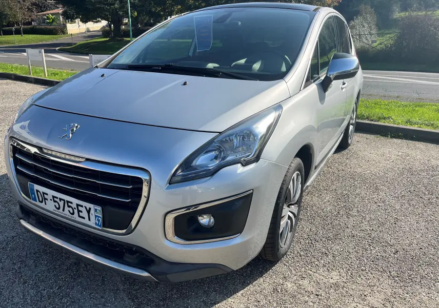 Peugeot 3008 gris clair vue 3/4 avant droit, mettant en valeur sa calandre chromée et ses phares distinctifs.