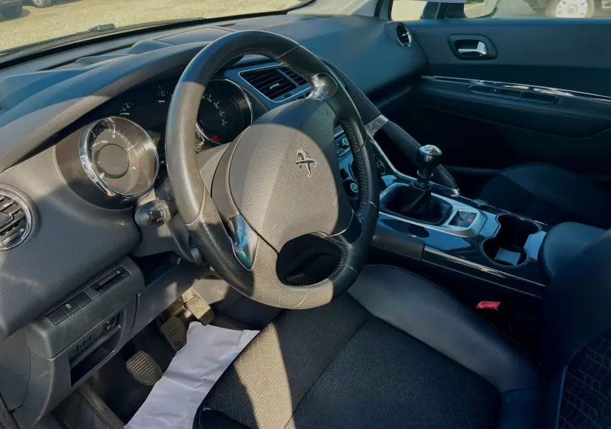 Intérieur noir du Peugeot 3008 2014, vue côté conducteur sur le volant cuir et levier de vitesse manuel.
