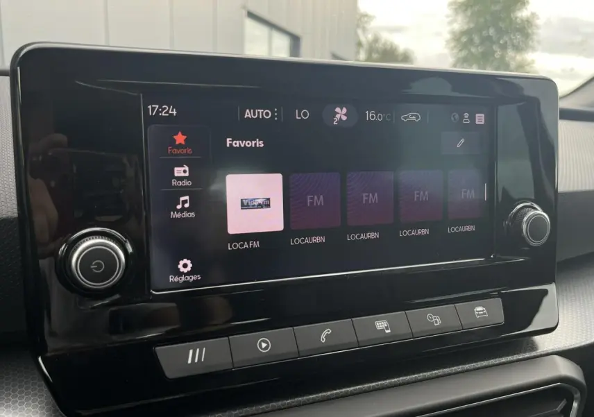 Écran tactile central du tableau de bord du SEAT Leon 2024 noir Minuit, affichant les favoris radio et commandes tactiles.