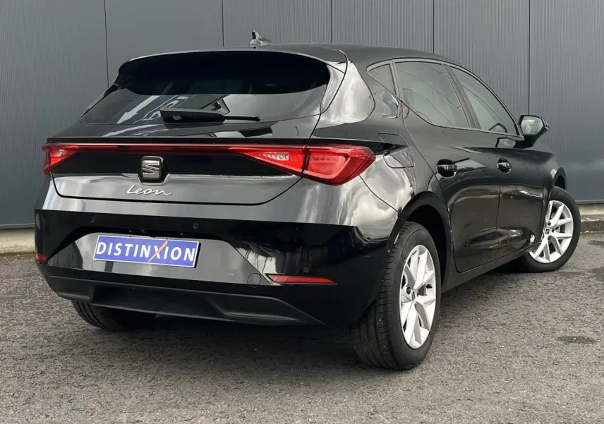 Vue 3/4 arrière droite d'une SEAT Leon 2024 noire Minuit avec feux arrière LED et jantes alliage 16 pouces.
