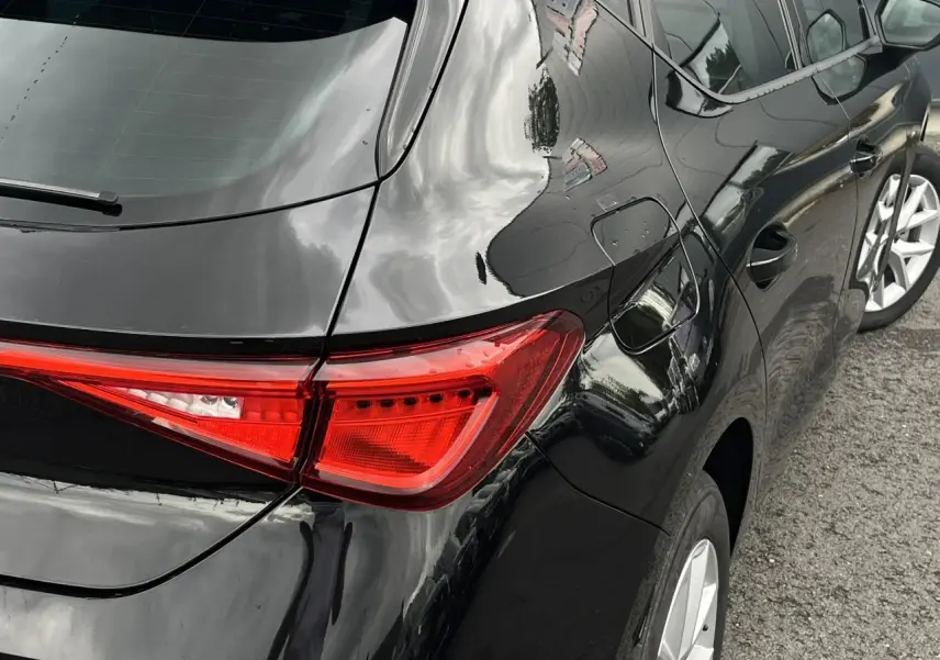 Gros plan sur l'arrière droit noir minuit d'une SEAT LEON 2024, mettant en valeur le feu arrière et la jante alliage.
