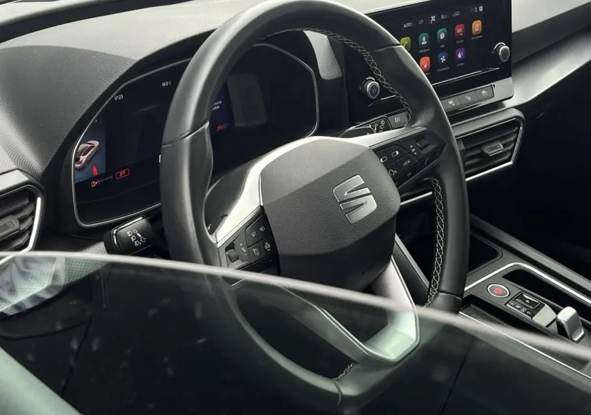 Vue intérieure centrée sur le volant cuir multifonction et l'écran tactile du tableau de bord d'une SEAT LEON 2024.