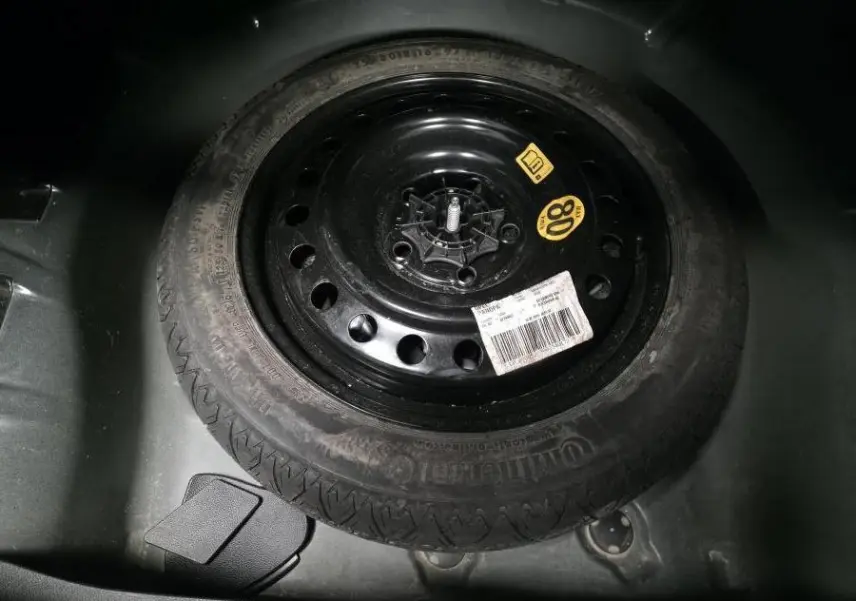 Gros plan sur la roue de secours noire 16 pouces du coffre de l'Opel Insignia 2016 avec étiquettes visibles.