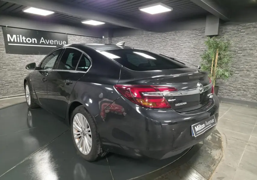 Vue 3/4 arrière droite d'une Opel Insignia noire métallisée avec vitres arrière teintées dans un showroom.