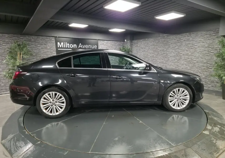 Opel Insignia noire vue de profil côté gauche, avec jantes alliage et vitres teintées en intérieur showroom.