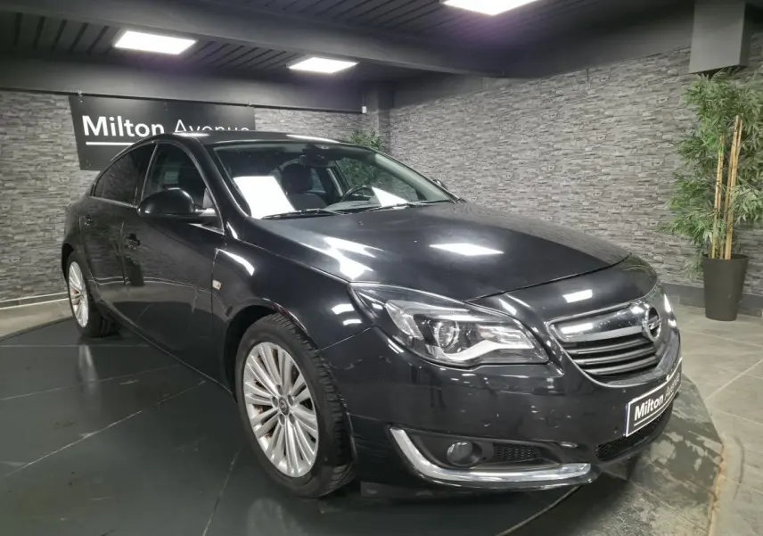 Opel Insignia noire vue en 3/4 avant droit, avec jantes alliage et calandre chromée dans un showroom.