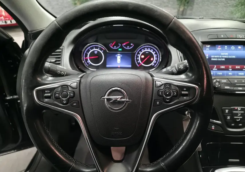 Volant cuir noir avec commandes intégrées et tableau de bord numérique d'une Opel Insignia 2016 vue de face intérieure.