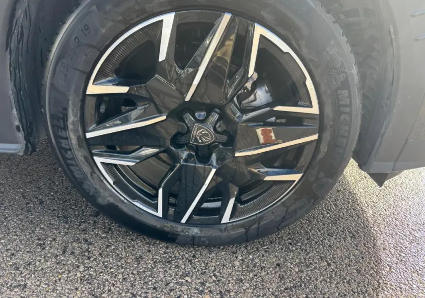 Gros plan sur la jante alliage noire et argentée de 19 pouces du Peugeot 3008 Hybrid gris, avec pneu Michelin visible.