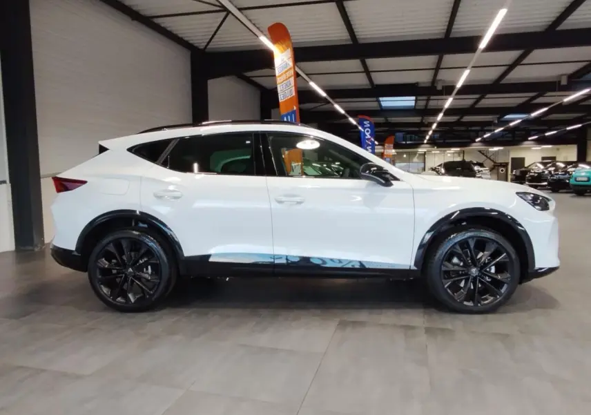 Vue de profil côté gauche du CUPRA Formentor blanc Nevada avec jantes alliage noires et bas de caisse contrastants noirs.