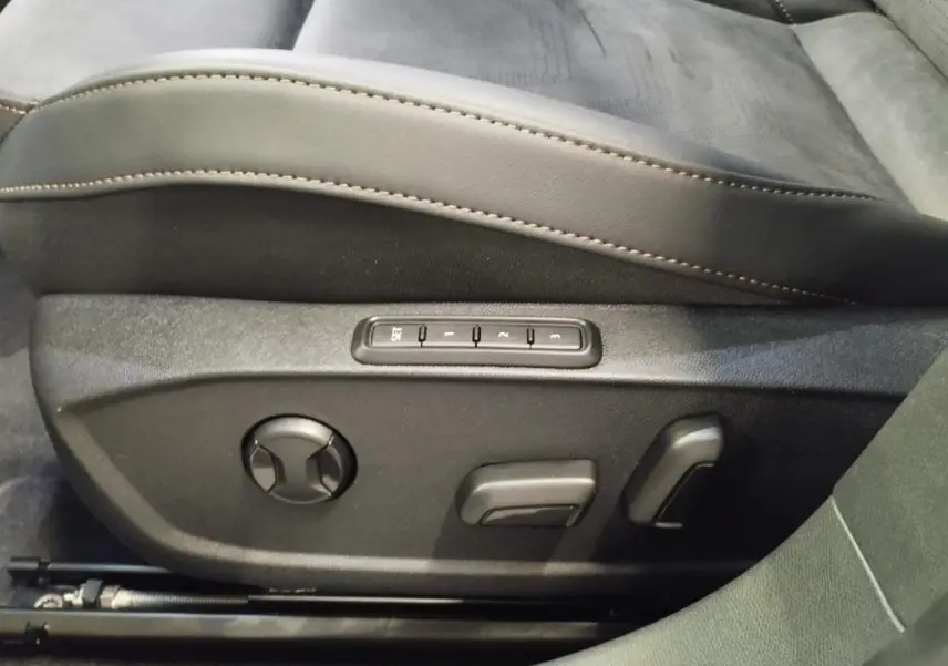 Gros plan sur les commandes de réglage électrique du siège conducteur en suédine noire avec surpiqûres cuivrées du CUPRA Formentor.