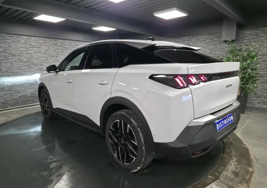 Peugeot 3008 blanc vue 3/4 arrière droit, jantes alliage noires et feux arrière LED 3 griffes allumés.