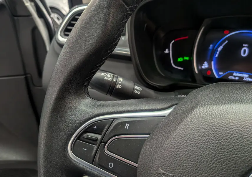 Gros plan sur le volant noir du Renault Kadjar 1.5 Blue dCi 115 CH BUSINESS, avec commandes intégrées et tableau de bord numérique visible.