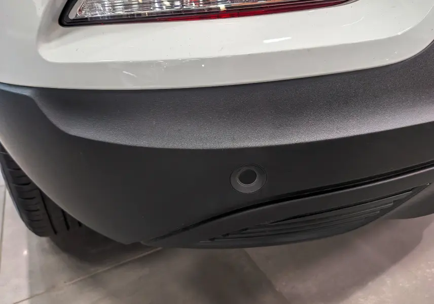 Gros plan sur le pare-chocs arrière noir et blanc glacier du Renault Kadjar 1.5 Blue dCi 115 CH BUSINESS avec capteur de recul.