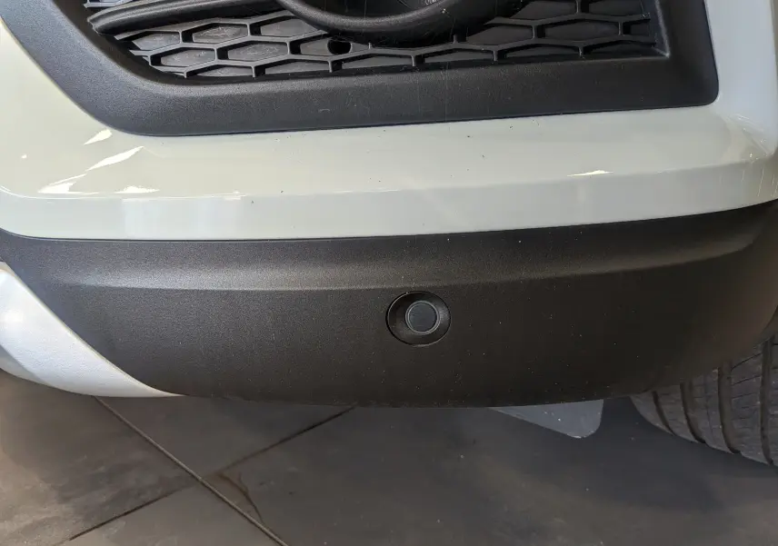 Gros plan sur le capteur de stationnement avant du Renault Kadjar blanc glacier, partie inférieure du pare-chocs visible.
