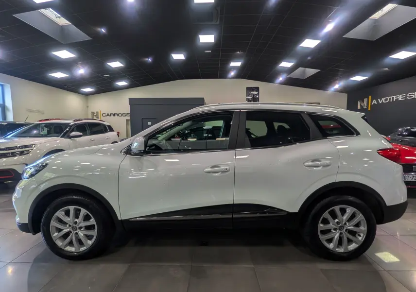 Profil côté gauche du Renault Kadjar blanc glacier 2020 en version Business, exposé en showroom lumineux.