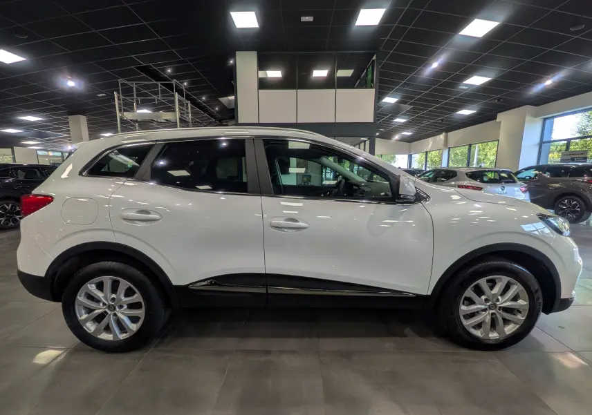 Renault Kadjar blanc Glacier vu de profil côté gauche dans un showroom lumineux avec jantes alliage.
