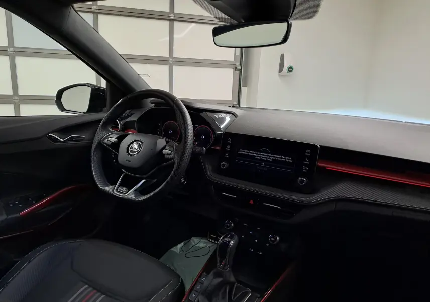 Intérieur avant droit de la Skoda Fabia 2024 noir Magic Nacré avec tableau de bord numérique et éclairage d'ambiance rouge.