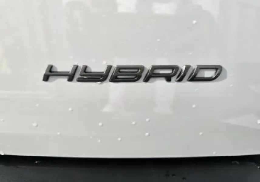 Gros plan sur l’inscription HYBRID noire sur la carrosserie blanche d’un Peugeot 2008 2025.