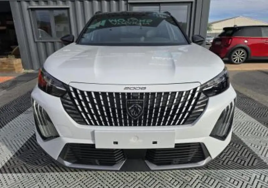 Vue frontale du Peugeot 2008 blanc Okenite avec calandre noire verticale et toit noir brillant.