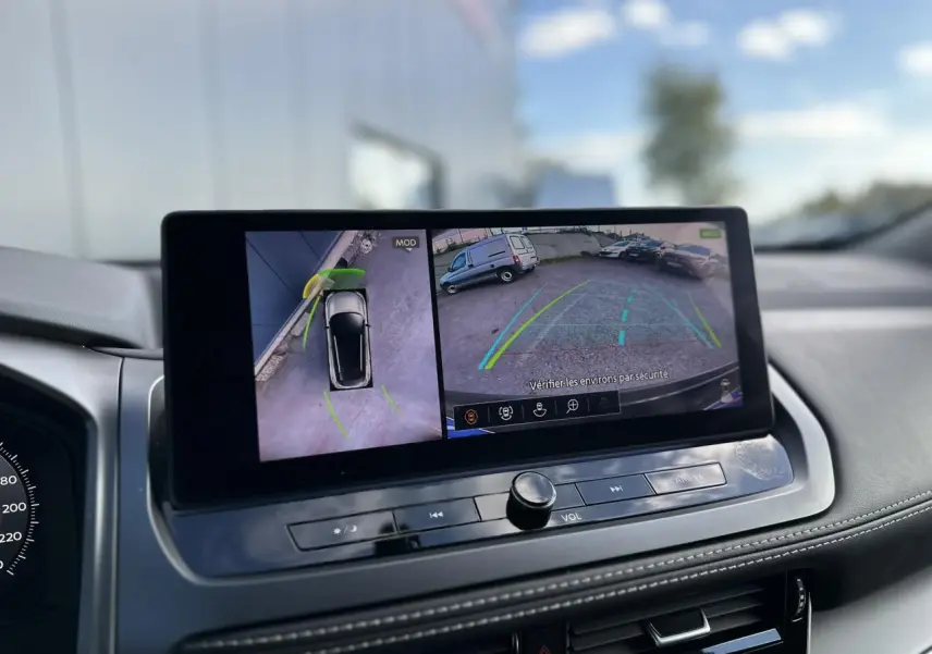 Écran central du Nissan Qashqai 2025 montrant la caméra de recul et la vue 360° du véhicule noir nacré en stationnement.