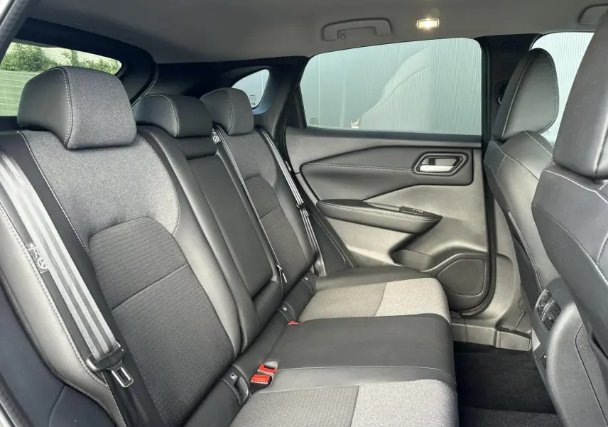 Vue intérieure côté droit des sièges arrière en tissu noir et gris du Nissan Qashqai 2025 avec ceinture à rayures.