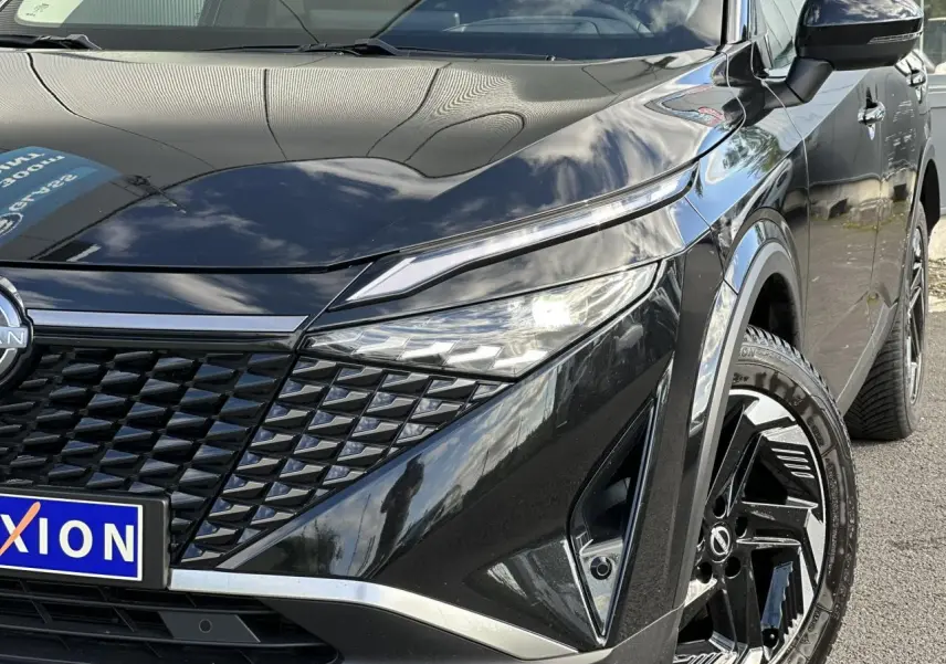 Vue 3/4 avant droit du Nissan Qashqai noir nacré mettant en valeur la calandre et les jantes alliage 18 pouces.