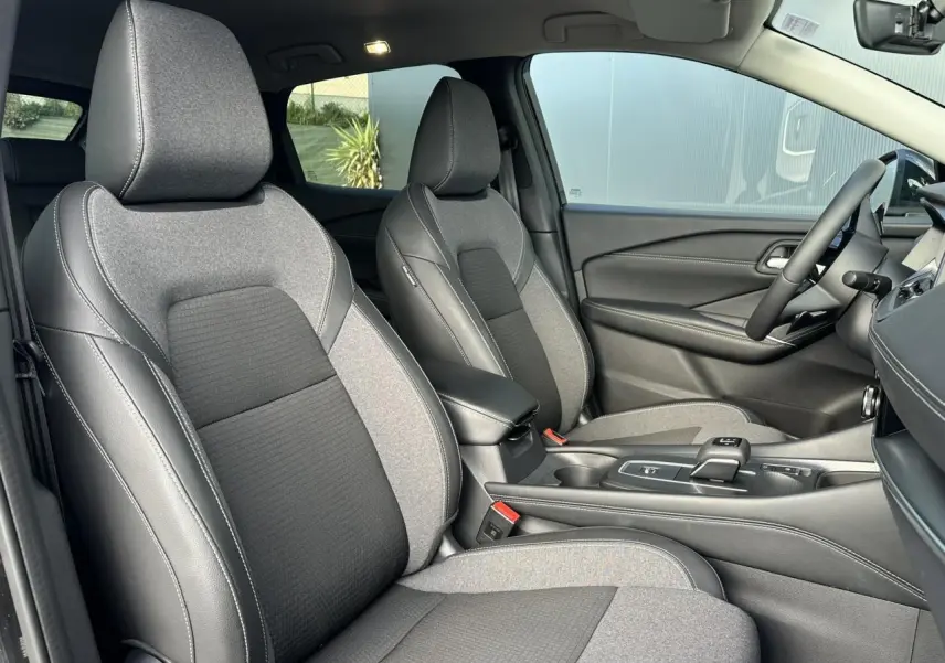 Intérieur du Nissan Qashqai 2025, vue côté droit sur sièges avant gris et noir avec console centrale moderne.
