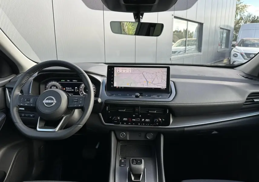 Intérieur du Nissan Qashqai 2025 vu de face, tableau de bord moderne avec écran tactile et volant cuir noir.