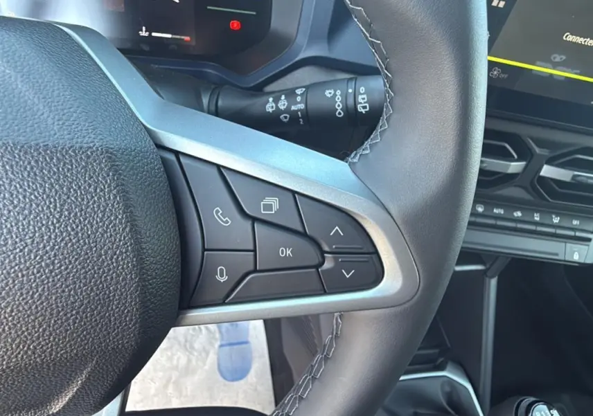 Gros plan sur le volant du Dacia Duster 2025 orange, montrant les commandes multifonctions côté gauche et partie du tableau de bord.